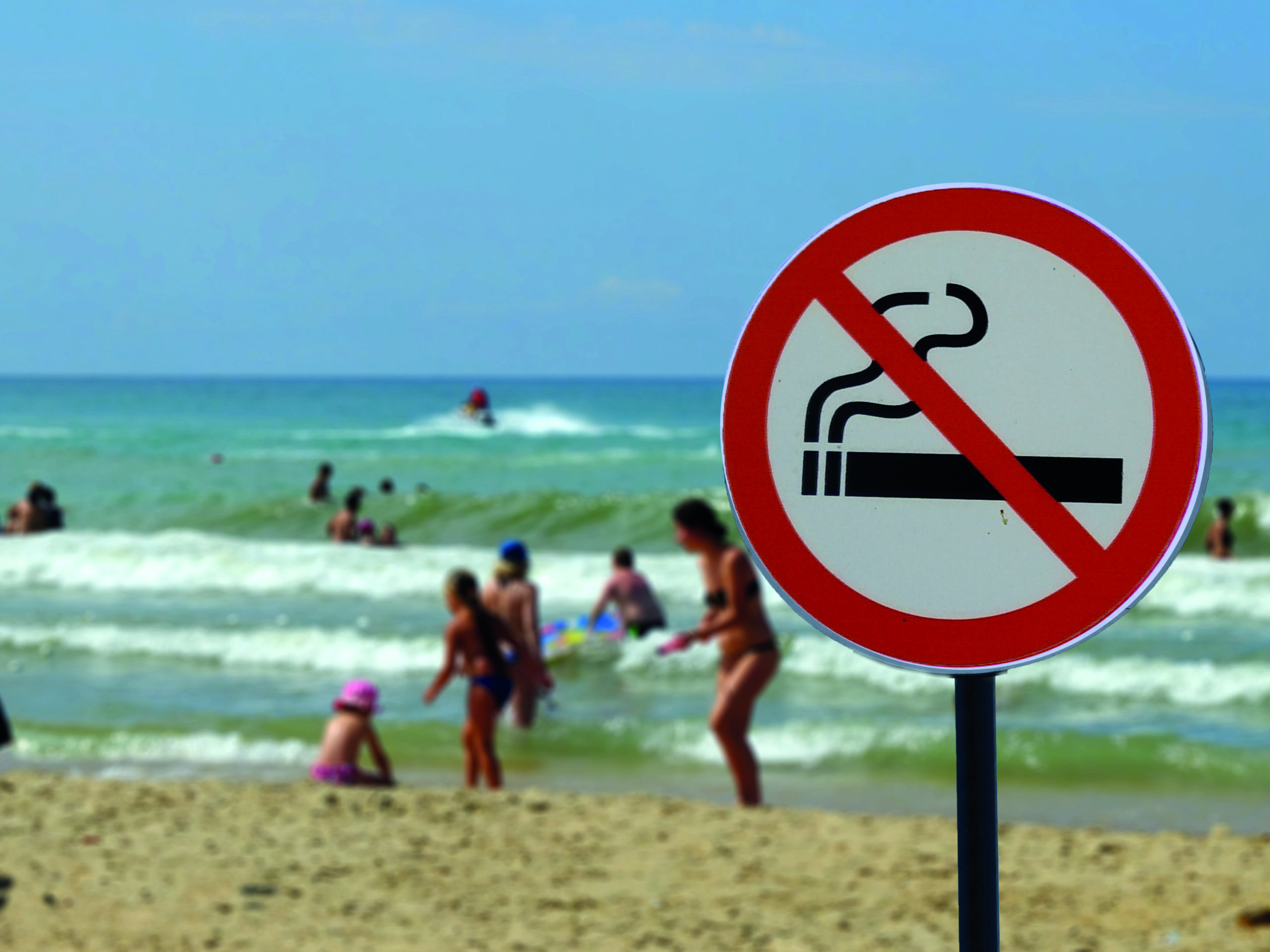 Sign Smoking is not allowed on the beach on the background of people in the sea.